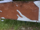 a brown wooden board with pieces of a white banner left